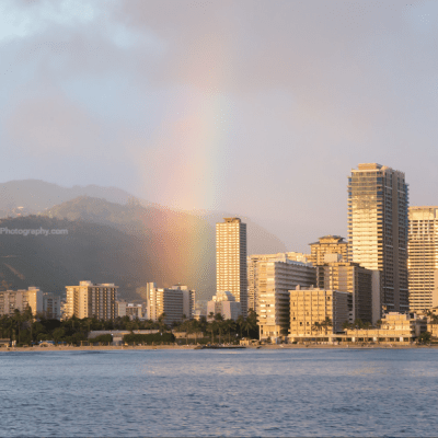 a rainbow over a body of water with a city in the background