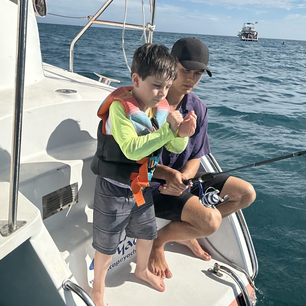 Child and adult fishing on a boat in the ocean.