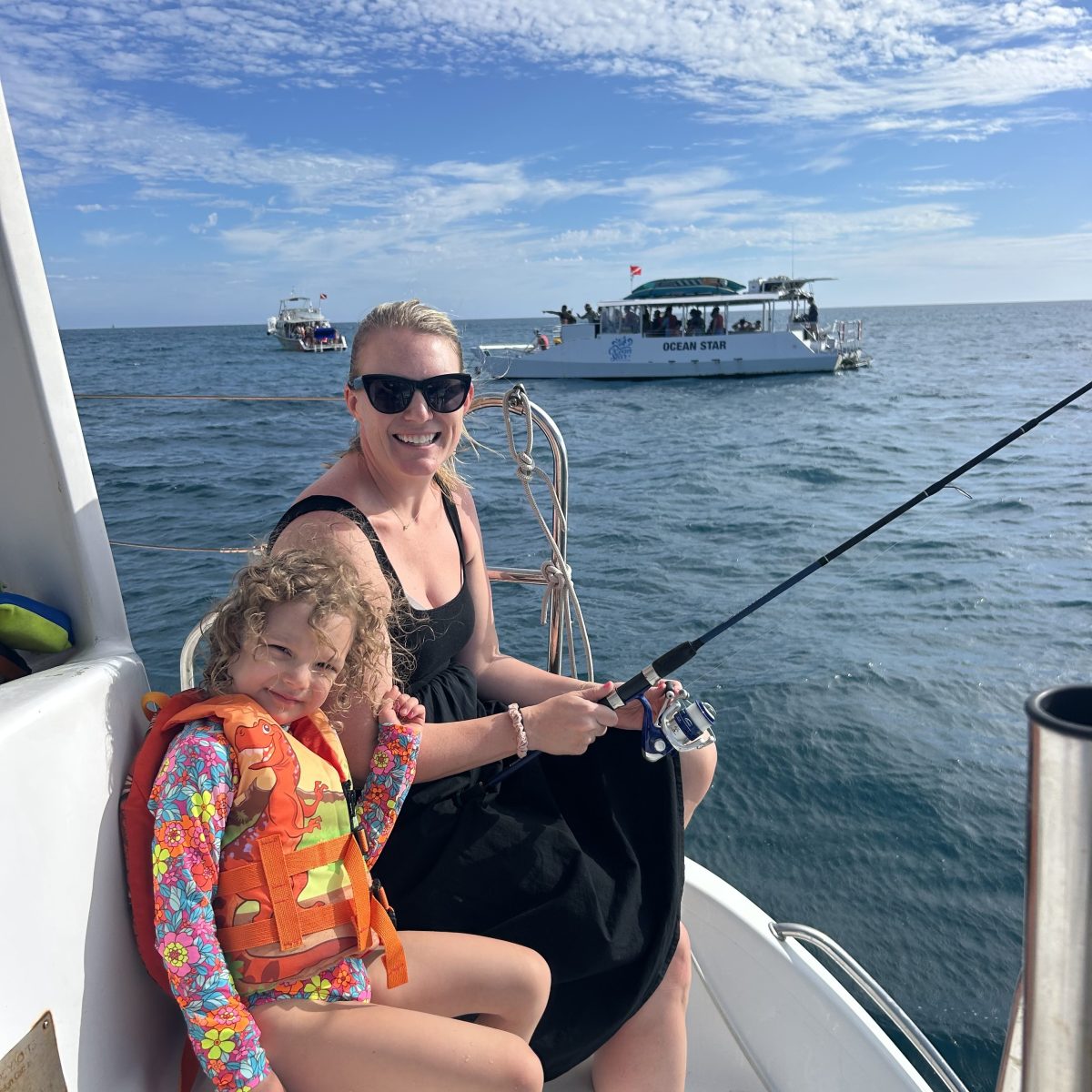 Woman and child fishing on a boat with life jacket, ocean view.