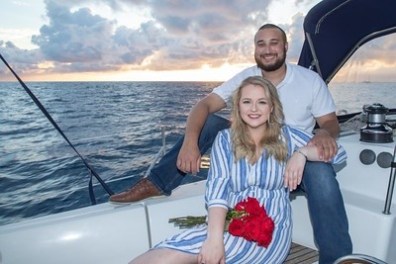 Couple on a sailing boat at sunset, woman holding red roses.