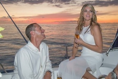 A couple on a boat at sunset, woman holding a drink and smiling.