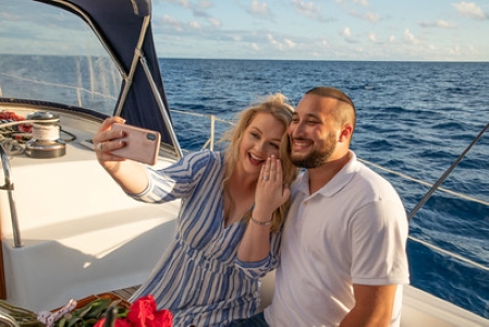 Couple taking a selfie on a sailboat with ocean in the background.